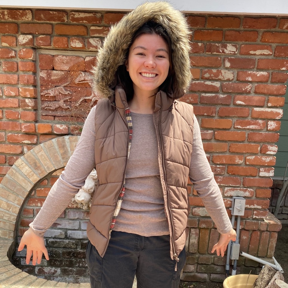Puffer vest with plaid lining and fake fur-lined hood. Hood can unzip from vest